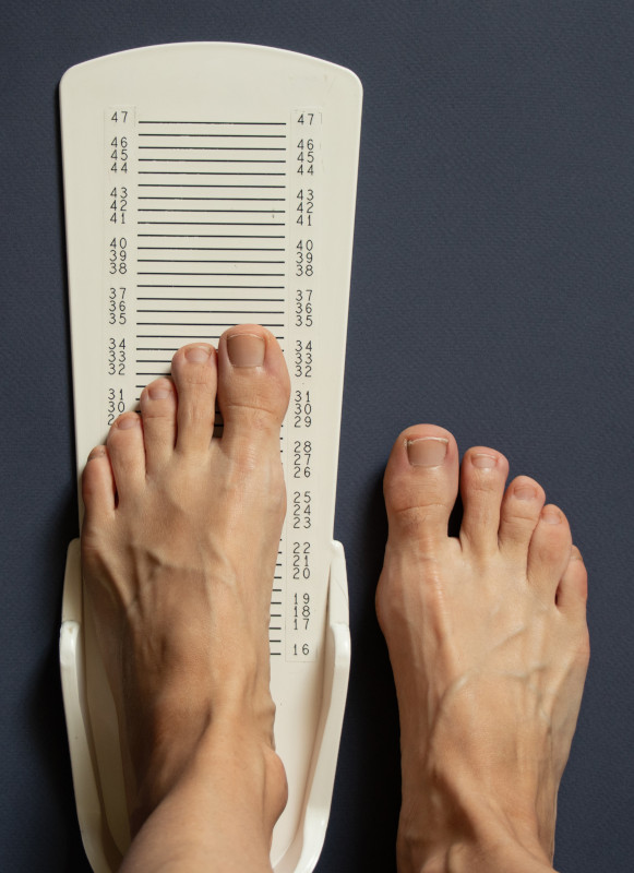 Measuring foot length with a sizing gauge.